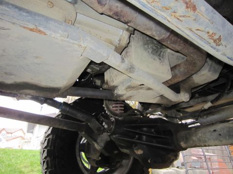 1996 Ford Bronco - The underside of a vehicle is visible, with focus on the suspension and drivetrain components.