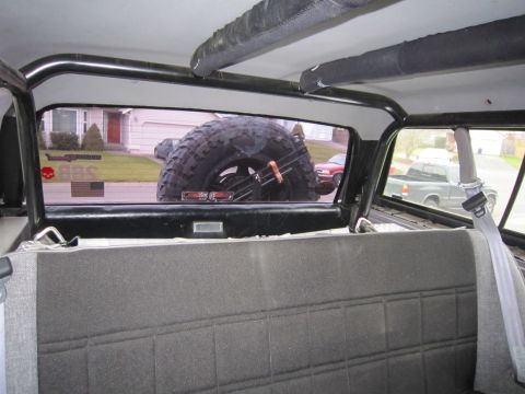 1996 Ford Bronco - View from inside a vehicle, showing a spare tire and the street scene outside.