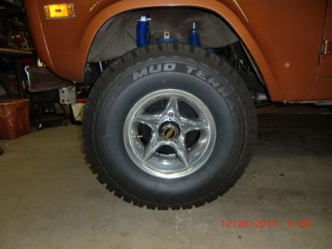 1973 Ford Bronco - The front wheel and fender of a 1973 Ford Bronco are shown, with aftermarket shocks and tires.