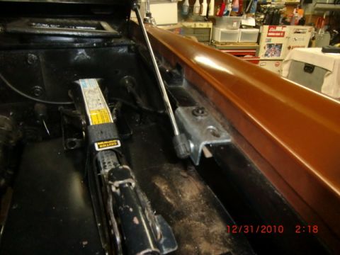 1973 Ford Bronco - Close-up of a car jack and mounting hardware within a vehicle's interior.