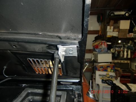 1973 Ford Bronco - The photo shows the interior of a vehicle's hood area, focusing on the hinge and strut assembly, with a garage visible in the background.