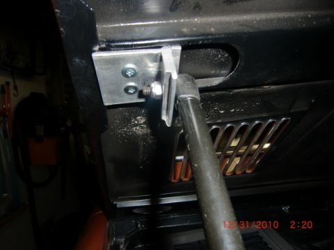 1973 Ford Bronco - Custom hood latch mechanism modification a gas strut mount and visible date stamp.