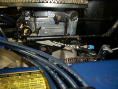 1973 Ford Bronco - A detailed view of engine parts, including a carburetor and spark plug wires, with an emissions control information sticker visible.