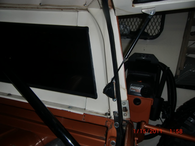 Interior of an orange and white vehicle with a black window and a Rigid chainsaw mounted inside