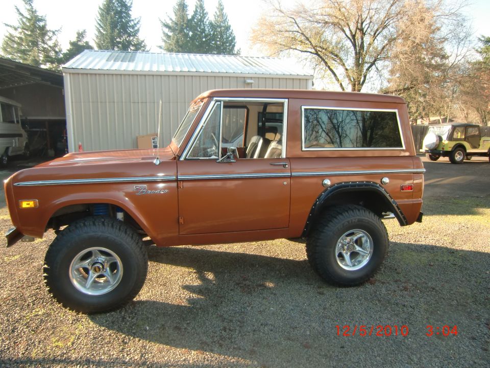 Brown 1973 Ford Bronco side view, lifted with chrome wheels