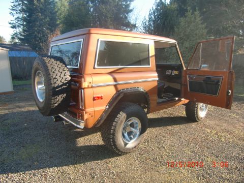 1973 Ford Bronco - A classic 1973 Ford Bronco sits parked on a gravel lot with its doors open, revealing the interior.