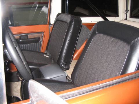 1973 Ford Bronco - The interior of a 1973 Ford Bronco shows orange door panels and black seats with a center console.