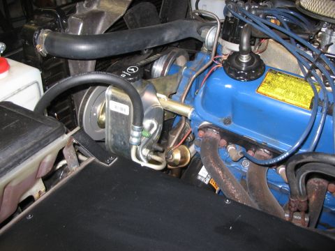 1973 Ford Bronco - Close-up view of the engine bay in a 1973 Ford Bronco, highlighting the blue valve covers and exhaust manifold.