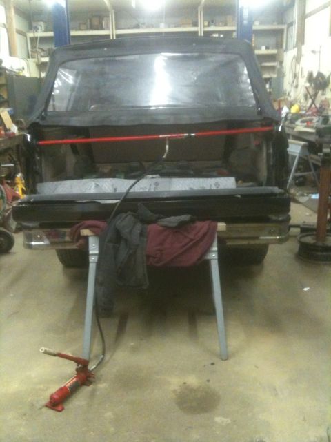 1993 Ford Bronco - The open tailgate of a Ford Bronco reveals its cargo space, with a red support bar across the opening.