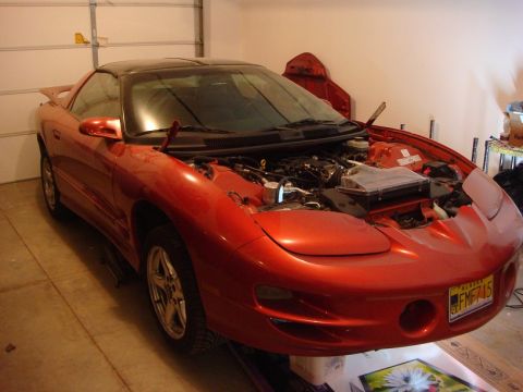2001 Pontiac Trans Am - Front view of a red 2001 Pontiac Trans Am in a garage, hood open to reveal the engine.