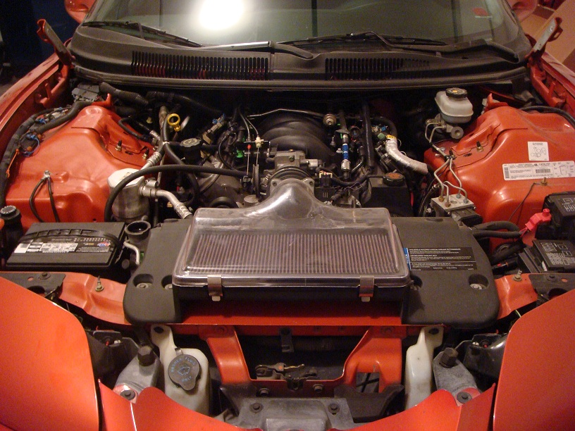 Red 2001 Pontiac Trans Am engine bay with exposed V8 engine, air intake, and battery