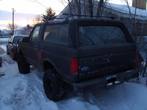 1995 Ford Bronco - A dark gray Ford Bronco is parked in a snowy area, viewed from the rear three-quarter angle.