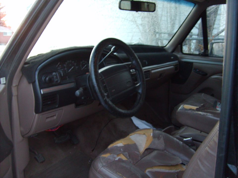 Interior of a 1995 Ford Bronco showing dashboard, steering wheel, and worn seats