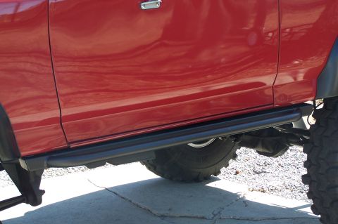 1990 Ford Bronco - The side of a red SUV is shown, black running boards and a portion of the rear tire.