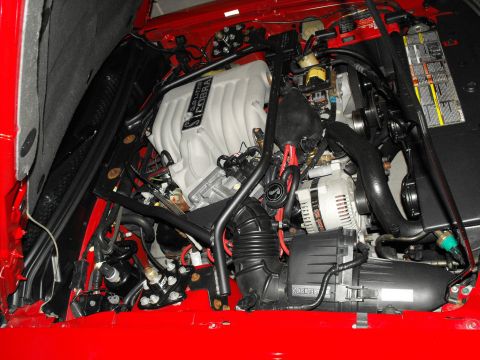 1994 Ford Bronco - Close-up of an engine bay a "5.0 Liter COBRA" intake manifold and red fender liners.
