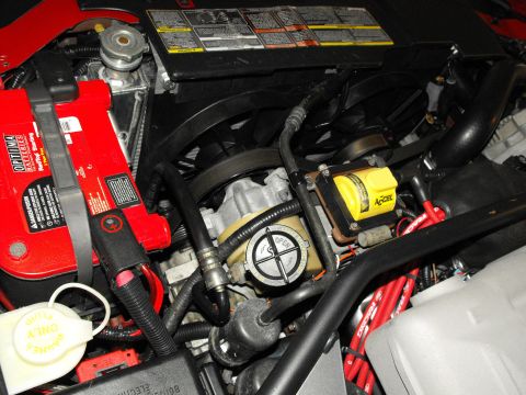 1994 Ford Bronco - Close-up view of an engine bay a red Optima battery and a yellow Accel ignition coil, with a SuperMotors.net watermark visible.