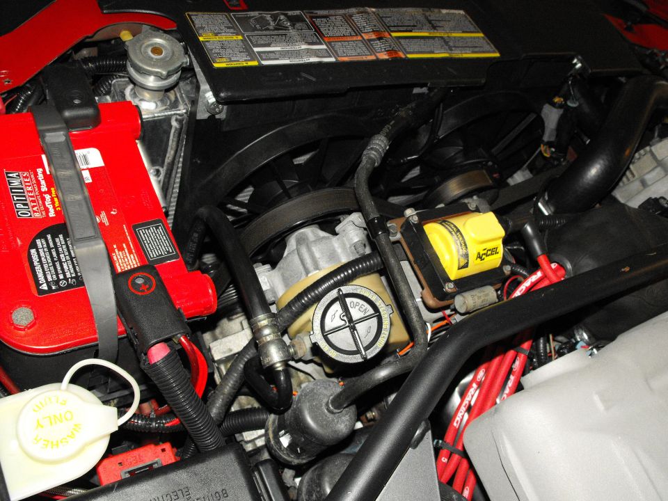 Engine bay with red Optima battery, yellow Accel ignition coil, and SuperMotors.net watermark