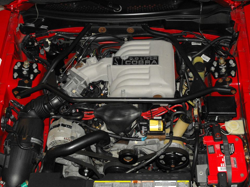 1994 Ford Mustang 5.0 Liter Cobra engine bay with red wiring and a bright red battery