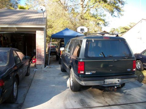 1994 Ford Explorer - Rear view of a dark green 1994 Ford Explorer parked in a driveway next to another car.