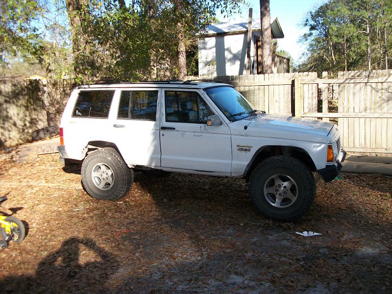 White Jeep Cherokee side view with aftermarket wheels and tires