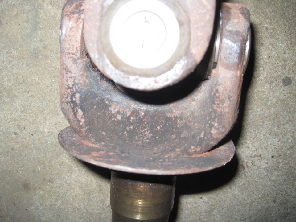 Close-up of a rusty driveshaft U-joint with a metal yoke