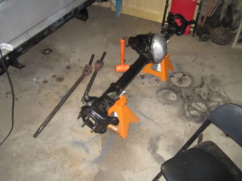 1979 Ford Bronco - Front axle assembly and driveshafts are shown disassembled and placed on jack stands in a garage setting.