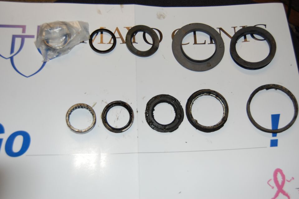 Wheel bearing and seal kit laid out on a white surface. Includes a bagged bearing, several metal rings, and rubber seals