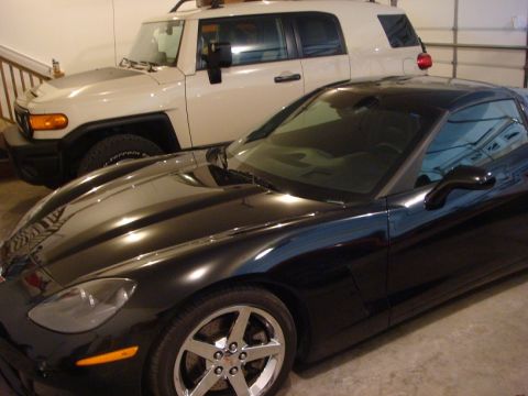 2001 Pontiac Trans Am - A black sports car is parked in a garage next to a white SUV, with the front quarter of the sports car prominently displayed.