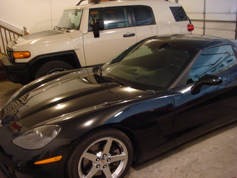Black sports car front quarter view, parked next to a white SUV