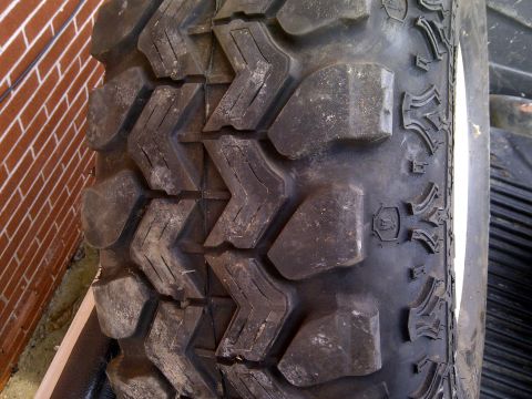 1990 Ford Bronco - A tire with aggressive tread patterns is shown against a brick wall.