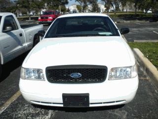 2002 Ford Crown Victoria - Front view of a white 2002 Ford Crown Victoria parked in a lot with another vehicle behind it.