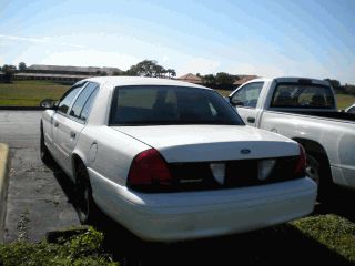 2002 Ford Crown Victoria - Rear view of a white 2002 Ford Crown Victoria parked next to a white pickup truck.