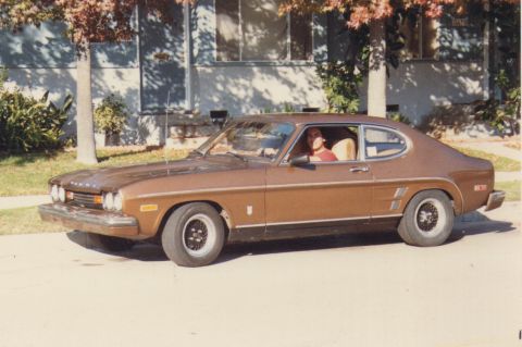 1968 Ford Mustang - A person is sitting in the driver's seat of a brown Ford Capri parked on a residential street.