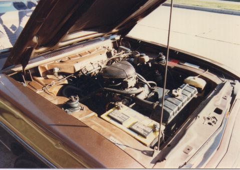 1968 Ford Mustang - The engine compartment of a brown vehicle is open, revealing the engine, battery, and radiator.