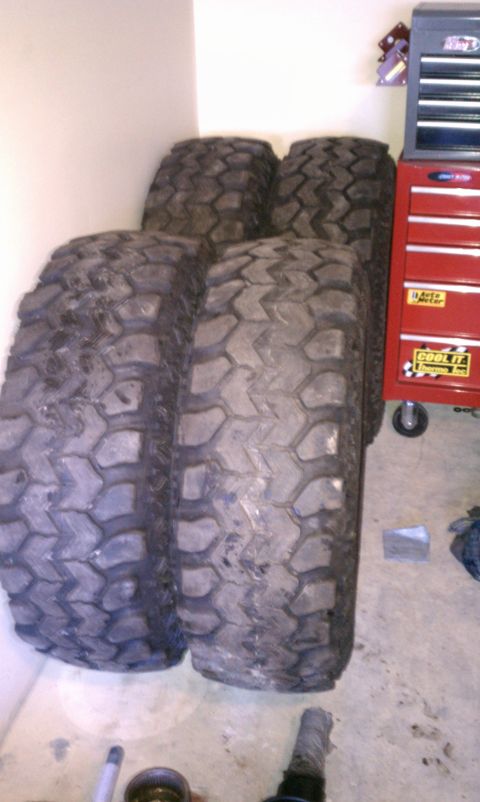 1990 Ford Bronco - A set of four off-road tires are stored indoors, awaiting their next adventure.