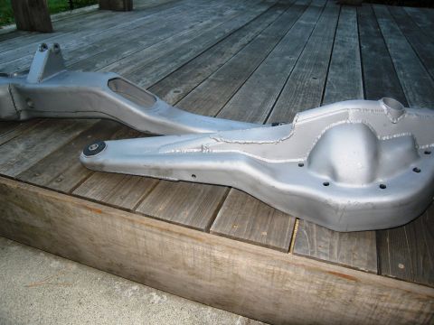 1986 Ford Bronco - Close-up of a vehicle's front axle housing and control arm resting on a wooden deck.