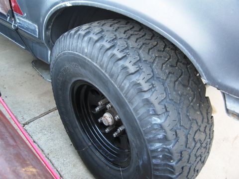 1986 Ford Bronco - A close-up view of a vehicle's tire and fender, with visible text on the tire.