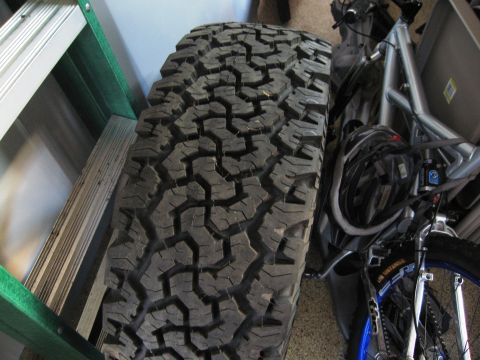 1986 Ford Bronco - Tire and bicycle parts are stored indoors next to a ladder.