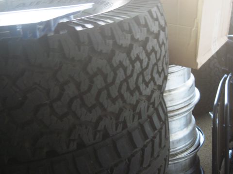 1986 Ford Bronco - A close-up view of a tire and stacked rims, with a cardboard box in the background.