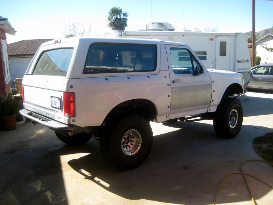 White 1996 Ford Bronco rear view with aftermarket bumper and large tires