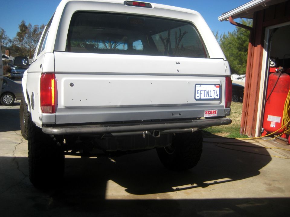 Rear view of a white 1996 Ford Bronco with a custom bumper and a California license plate reading 5FTN174