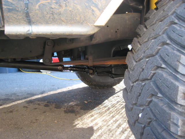 Truck undercarriage with large tire, leaf springs, and steering linkage visible
