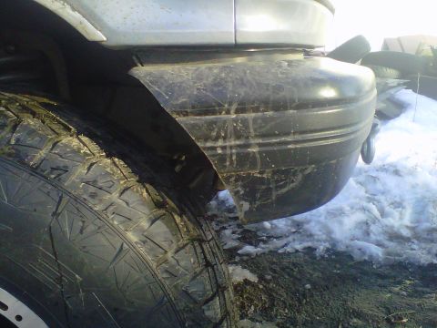 1994 Ford F-150 - Close-up of the front corner of a dirty silver pickup truck, showing the fender and bumper.