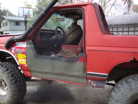 1986 Ford Bronco - This 1986 Ford Bronco features a snorkel, large off-road tires, and various aftermarket decals on its door.