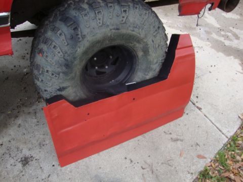 1986 Ford Bronco - Red fender flare fitted around a large tire, likely for an off-road vehicle modification.