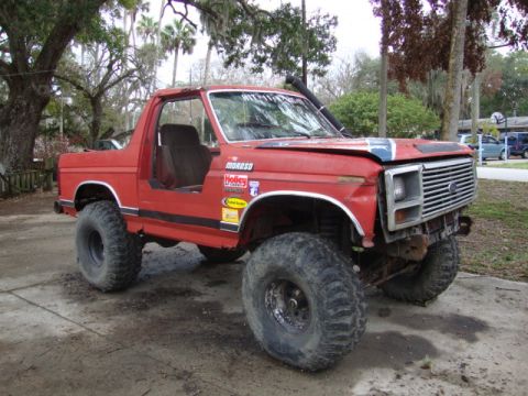 1986 Ford Bronco - This lifted Ford Bronco has off-road tires and several decals on its side and hood.