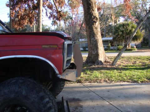 1986 Ford Bronco - The front end of a red truck is shown with a new bumper under construction.