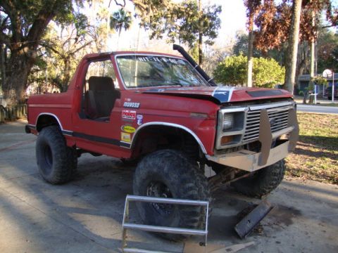 1986 Ford Bronco - Modified red 1986 Ford Bronco features a custom front bumper, snorkel, and lifted suspension.