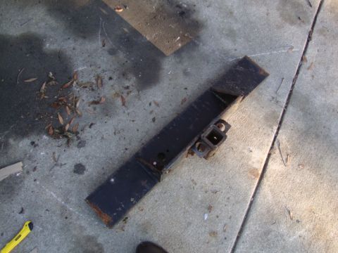 1986 Ford Bronco - Trailer hitch receiver lying on a concrete surface with scattered leaves.