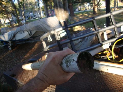1986 Ford Bronco - A hand holds a pipe, obscuring a covered boat on a trailer in the background.